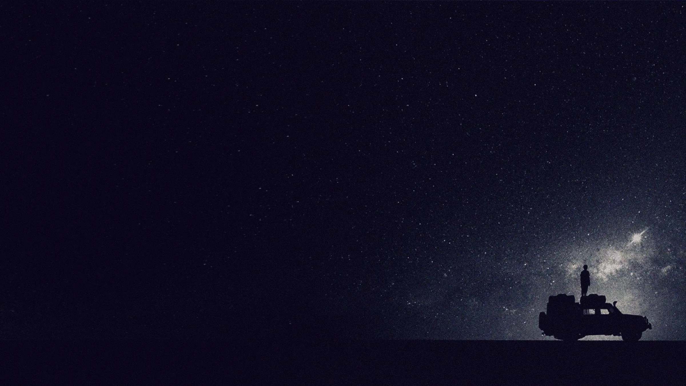A lone figure on a vehicle beneath the Milky Way